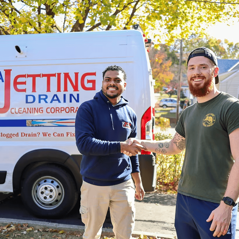A USA Jetting technician shaking hands with a customer beside the service van